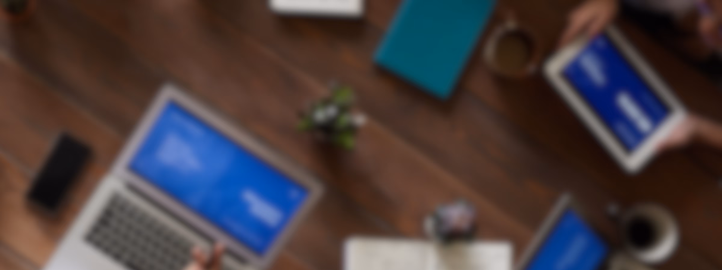 Top-Down-Ansicht von Fachkräften, die mit Laptops, Tablets, Notebooks und digitalen Präsentationen an einem Besprechungstisch zusammenarbeiten. Im Vordergrund stehen dabei strategische Planung, geschäftliche Zusammenarbeit, Projektmanagement, datengestützte Entscheidungsfindung und effektive Teamarbeit in einem modernen Unternehmensumfeld.