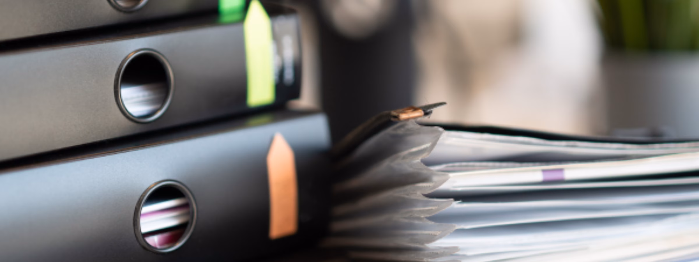 Übersichtlich angeordnete Ordner und Stapel von Geschäftsunterlagen auf einem Schreibtisch, die Dokumentenmanagement, Compliance-Aktenführung, Qualitätssicherung, behördliche Dokumentation und effiziente Informationsorganisation in einem professionellen Geschäftsumfeld verdeutlichen.