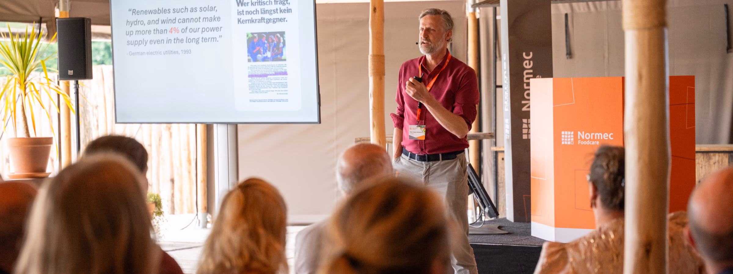 A speaker delivers a presentation to an audience during a professional food industry seminar, with presentation slides displayed on a screen, highlighting food safety, quality assurance, regulatory compliance, industry insights, and knowledge sharing among food sector professionals.