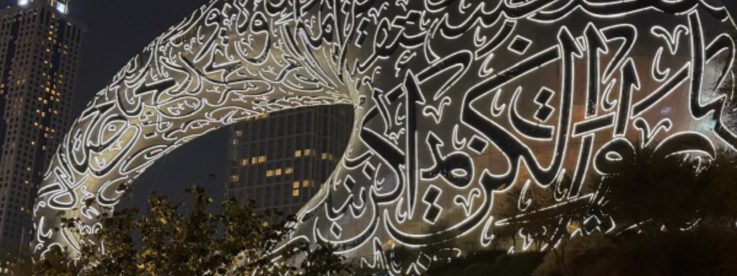 Das Museum der Zukunft in Dubai, dessen markante Fassade nachts von filigranen arabischen Kalligraphie-Motiven beleuchtet wird, symbolisiert Innovation, Technologie, das Wachstum des internationalen Handels und die Entwicklung globaler Märkte.