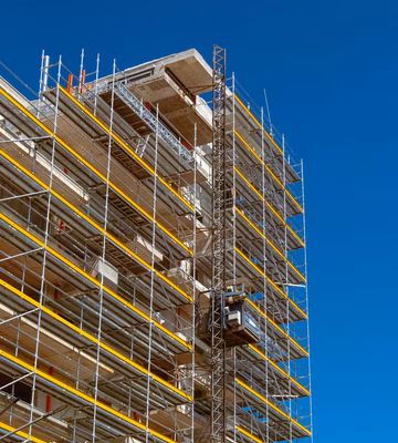 Structure d'échafaudage autour d'un bâtiment en construction pour les travaux sur la façade et les étages supérieurs.