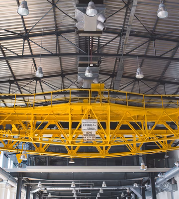 Pont roulant jaune dans un hall de production industriel, destiné au déplacement de matériaux et d'équipements.