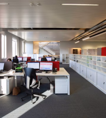 Espace de bureau moderne où les employés travaillent à leurs postes dans un environnement de travail ouvert.