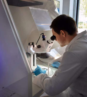 Ein Laborassistent führt in einem Untersuchungslabor eine Analyse mit einem Mikroskop durch.
