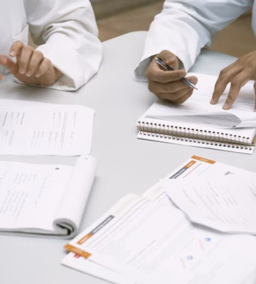 Professionals are discussing documents and taking notes during a meeting at a conference table.