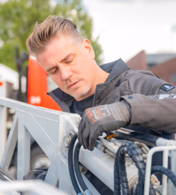 Technisch medewerker voert onderhouds- of inspectiewerkzaamheden uit aan een industriële constructie met kabels en technische componenten.