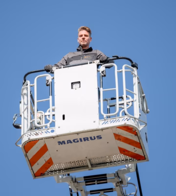 Technisch medewerker werkt vanuit een hoogwerker aan inspectie- of onderhoudswerkzaamheden op hoogte.