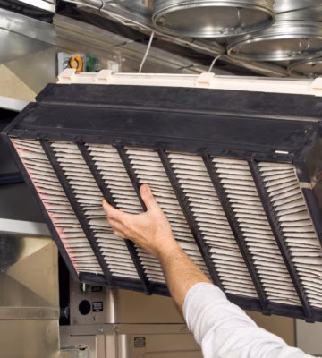 Un technicien installe un filtre à air dans une unité CVC lors de la mise en place du système de ventilation.