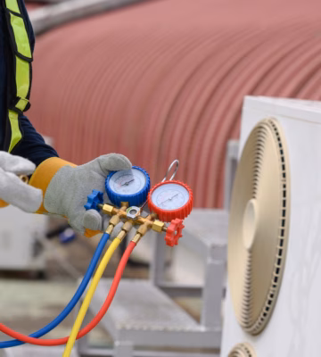 Un technicien effectue l'entretien de climatiseurs à l'aide d'un kit de raccords.