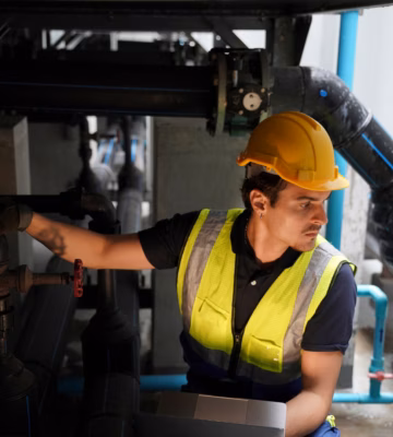 Een medewerker controleert leidingen en afsluiters binnen een technische installatie.