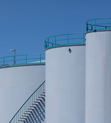 Grands réservoirs de stockage équipés d'escaliers d'accès et de garde-corps sur un site industriel.