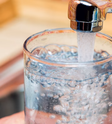Un verre est rempli d'eau du robinet dans le cadre de la consommation d'eau potable et de la qualité de l'eau.