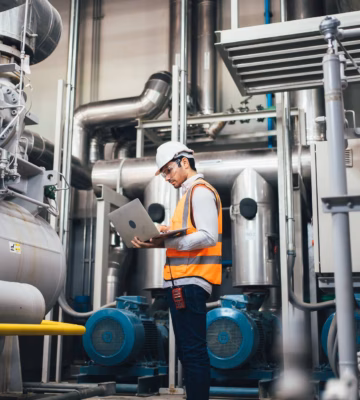 Un technicien contrôle une installation industrielle et enregistre les données d'inspection à l'aide d'un ordinateur portable.