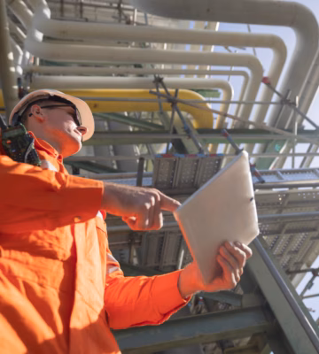 Un technicien procède à l'inspection d'une installation industrielle à l'aide d'une tablette.