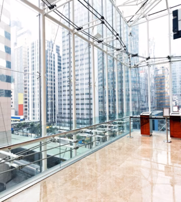 Intérieur d'un immeuble de bureaux moderne avec des structures en verre, une vue sur des gratte-ciel et un mur végétal.