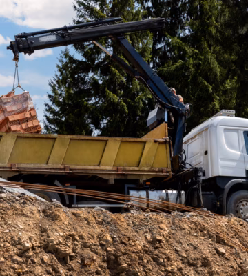 Een vrachtwagen met kraan verplaatst bouwmaterialen op een bouwplaats.