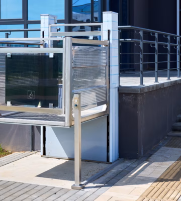 Une plate-forme élévatrice offre un accès facilité à côté d'un escalier, à l'entrée d'un bâtiment moderne.