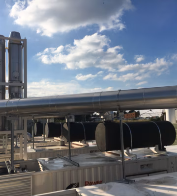 Technische installatie met metalen luchtkanalen en leidingen in een industriële omgeving.