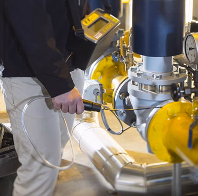 Technicus voert een inspectie uit aan industriële leidingen en een afsluiter binnen een technische installatie.