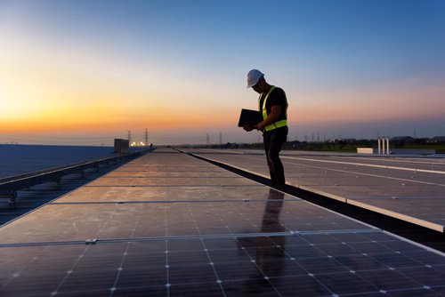 Inspection of solar panels at a solar farm or on a large roof surface using a tablet for monitoring and maintenance.