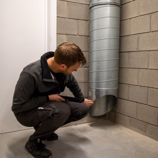 Technicus controleert een ventilatiekanaal in een technische ruimte tijdens inspectie- of onderhoudswerkzaamheden.