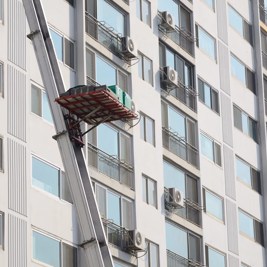 Entretien de la façade d'un immeuble de grande hauteur à l'aide d'une nacelle élévatrice placée à l'extérieur du bâtiment.