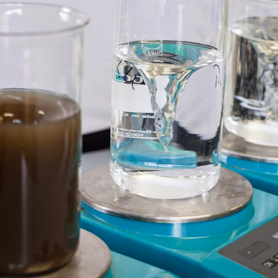 Troebel watermonster naast glazen bekers met helder vloeibaar monster op een laboratoriumweegschaal voor wateranalyse.