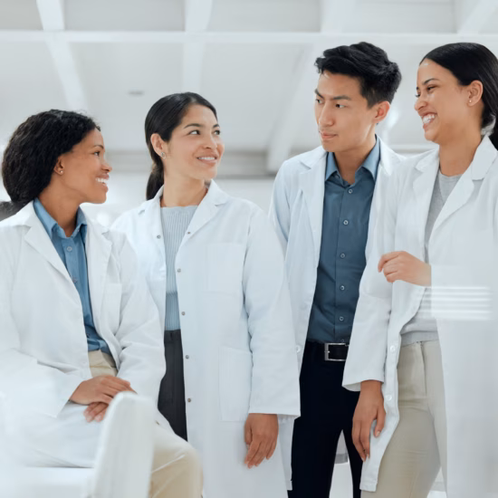 4 scientists in lab coats laughing in a laboratory