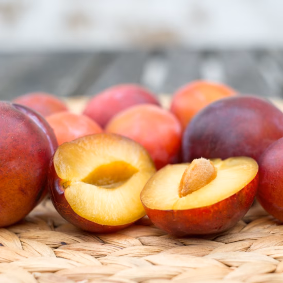 Rijpe nectarines, waarvan enkele gehalveerd zijn, op een gevlochten ondergrond.