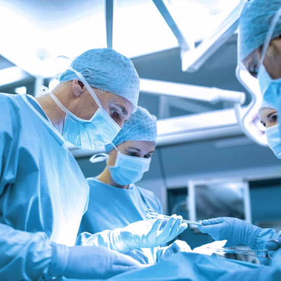 A group of doctors are operating in a medical room while performing surgery.