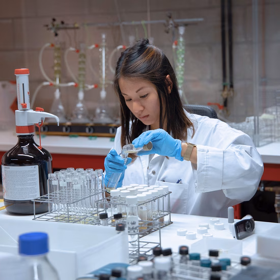 Laboratoriummedewerker voert een analyse uit met een pipet en reageerbuisjes in een onderzoekslaboratorium.