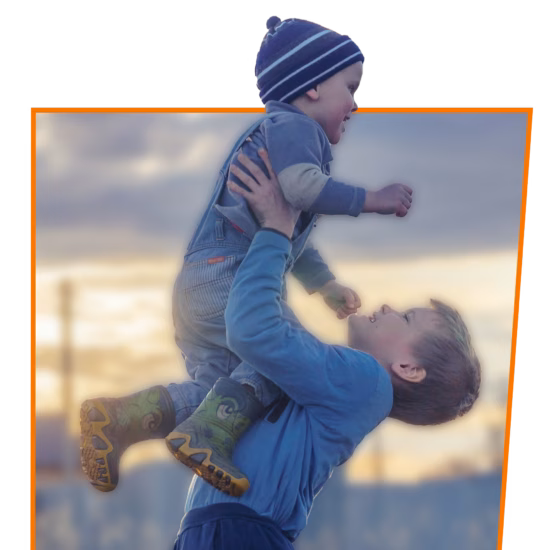 Two children are playing and laughing, with one child lifting the other.