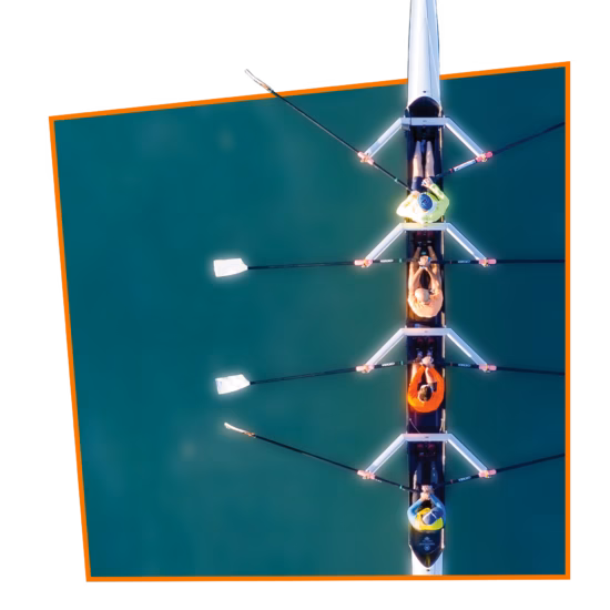 People are rowing a canoe on the water, seen from an aerial view.