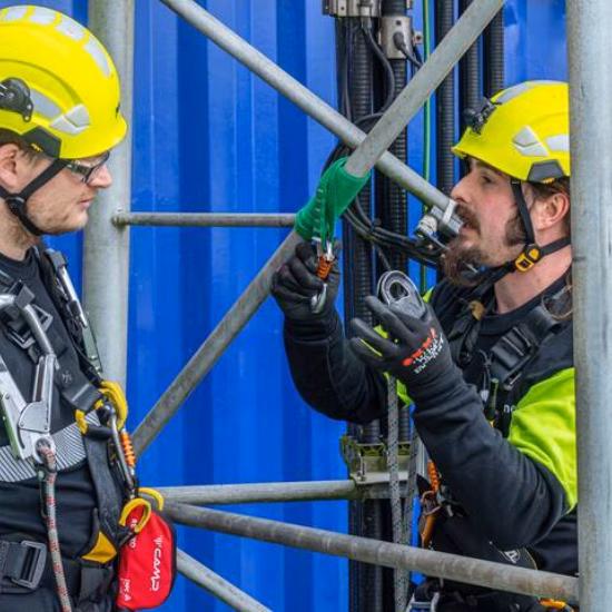 A man is securing himself with a safety harness during industrial fire fighting training, wearing a helmet.