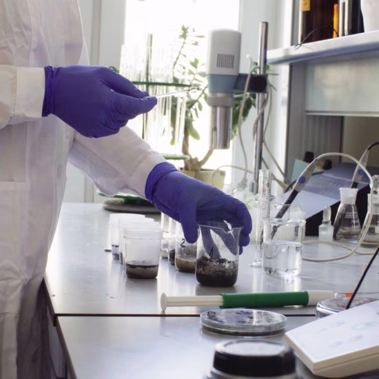 A laboratory technician prepares a sample for analysis at a laboratory bench equipped with measuring and testing equipment.