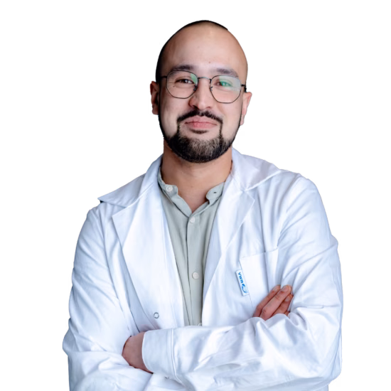 A smiling man is wearing a white lab coat with his arms crossed.