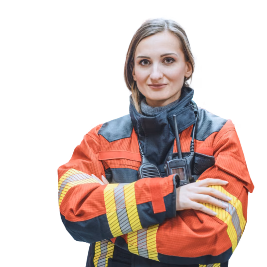 A firefighter woman is standing in front of a fire truck with her arms crossed.