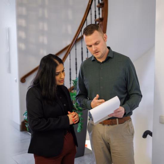 Man and woman standing together in an office hallway discussing work.