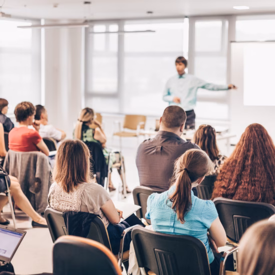 Deelnemers luisteren naar een presentatie tijdens een training of seminar in een moderne lesruimte.