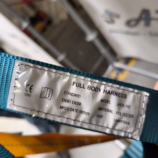 Nahaufnahme eines aufgenähten Identifikationsetiketts an einer industriellen Hebeschlinge, auf dem Produktinformationen, Zertifizierungszeichen, Lastangaben und Sicherheitsdetails zu sehen sind. Das Etikett unterstreicht die Rückverfolgbarkeit des Produkts, die Einhaltung gesetzlicher Vorschriften, die Qualitätssicherung sowie die Zertifizierung der Hebevorrichtungen, die im industriellen Materialumschlag eingesetzt werden.