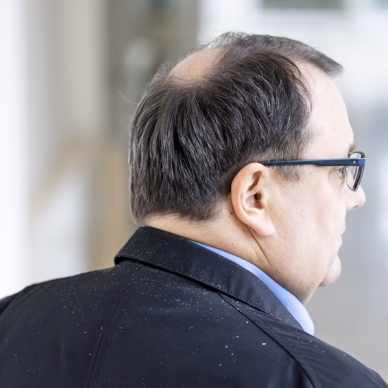 A person in work attire walks through a well-lit healthcare or research facility, illustrating a work environment focused on collaboration, innovation, and clinical excellence.