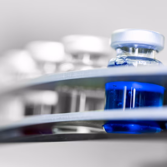 Blue laboratory vials are placed into an automated analysis system in a modern research laboratory that specializes in precise sample processing, pharmaceutical testing, and state-of-the-art scientific methods.