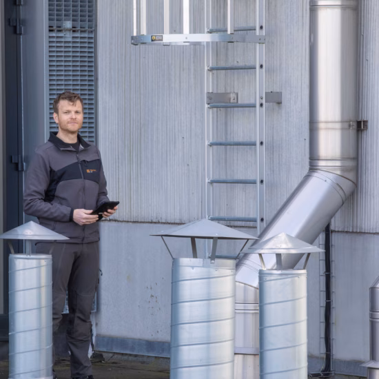 Inspecteur controleert rookgasafvoeren en ventilatievoorzieningen bij een gebouw in het kader van CO-convenant begeleiding en veilige verbrandingstoestellen.