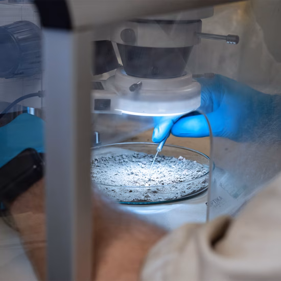 Un technicien de laboratoire examine un échantillon de matériau au microscope lors d'une analyse de la qualité de l'air