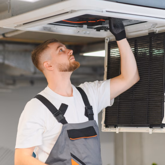 Monteur installeert een plafond‑airco en plaatst onderdelen in de open unit.