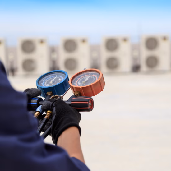Monteur gebruikt koeltechnische apparatuur tijdens onderhoudswerkzaamheden aan meerdere airconditioningunits.
