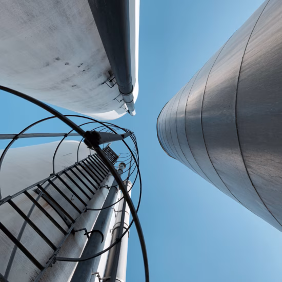 Onderaanzicht van industriële opslagtanks met leidingwerk en toegangsladder.