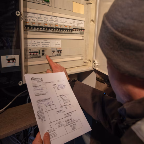 Un technicien vérifie un tableau de distribution électrique à l'aide d'un schéma d'installation.