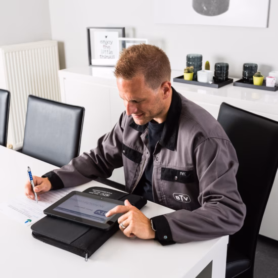 Un technicien consigne les données relatives à une intervention d'installation à l'aide d'une tablette et d'un formulaire.