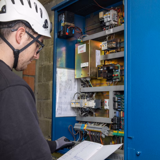Een inspecteur controleert een industriële besturingskast en documenteert de technische installatie.